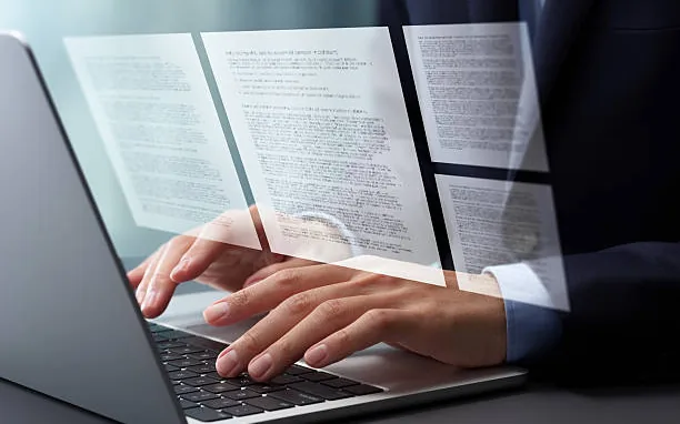 Hands typing on a laptop while preparing documents